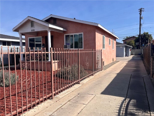 bungalow with a fenced front yard and stucco siding