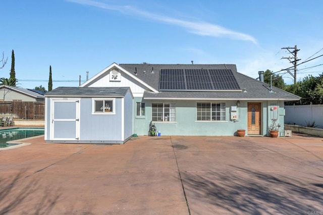 rear view of property with an outbuilding, roof mounted solar panels, a fenced backyard, and a patio