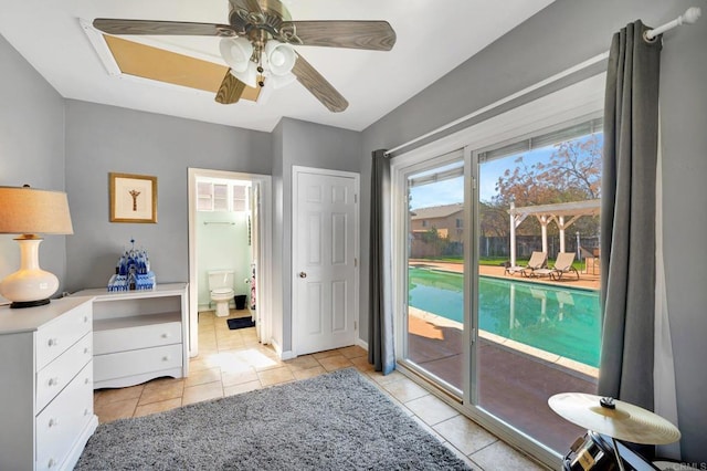 bedroom with access to exterior, light tile patterned floors, ceiling fan, ensuite bath, and baseboards