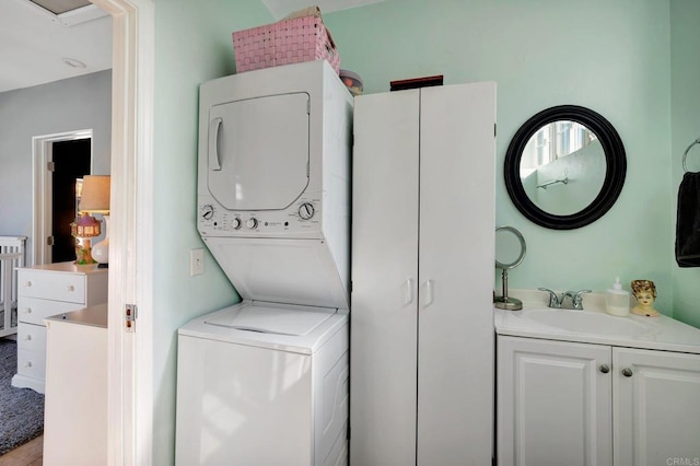 clothes washing area featuring stacked washer and clothes dryer, a sink, and laundry area