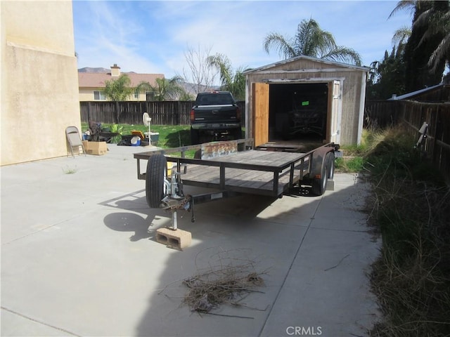 view of patio / terrace with an outbuilding, a storage unit, a fenced backyard, and a grill