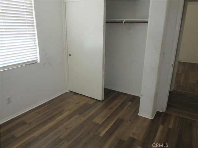 unfurnished bedroom featuring a closet and dark wood-style flooring