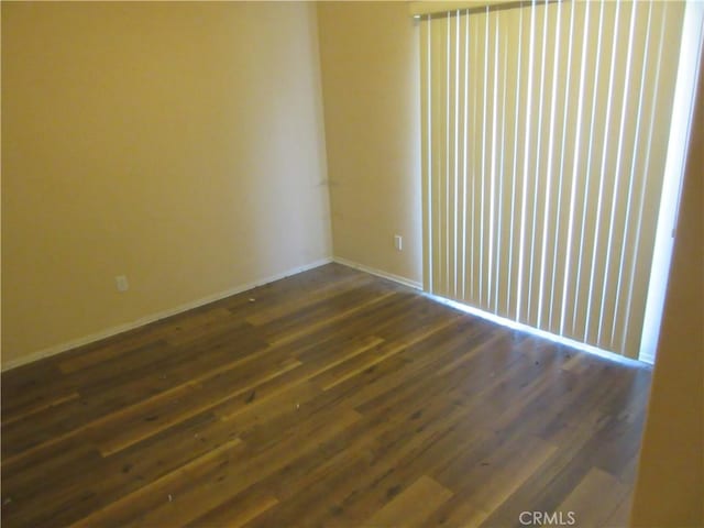 empty room with baseboards and dark wood-style flooring