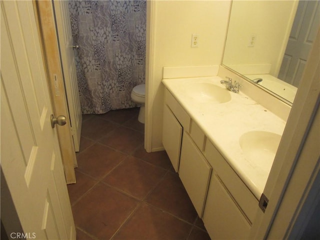 full bath featuring double vanity, a sink, toilet, and tile patterned floors