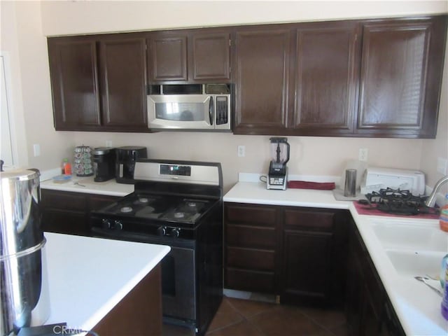 kitchen with light countertops, dark brown cabinets, stainless steel microwave, and range with gas cooktop