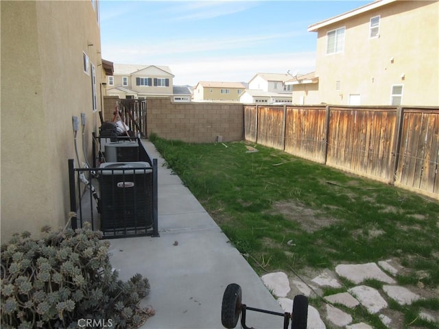 view of yard featuring a residential view, central AC, a patio, and a fenced backyard