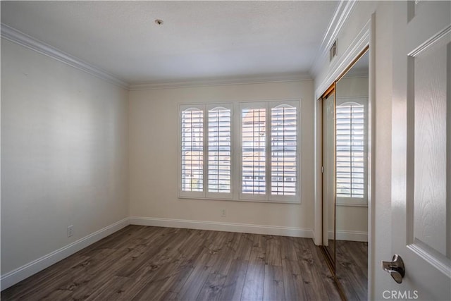 unfurnished room featuring dark wood-style floors, visible vents, baseboards, and crown molding