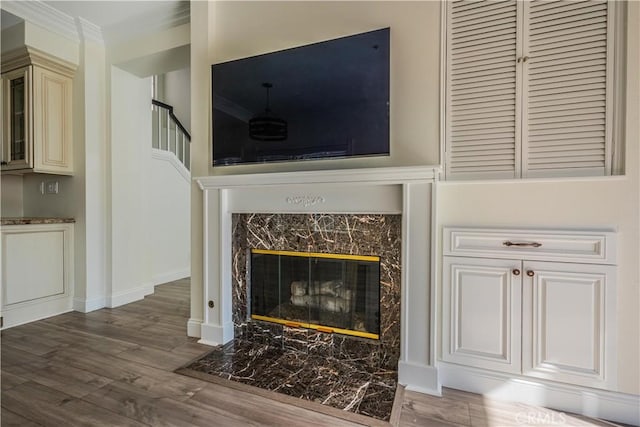 unfurnished living room with a high end fireplace, baseboards, and wood finished floors