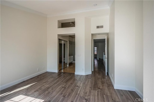 unfurnished bedroom with dark wood-style floors, visible vents, ornamental molding, and baseboards