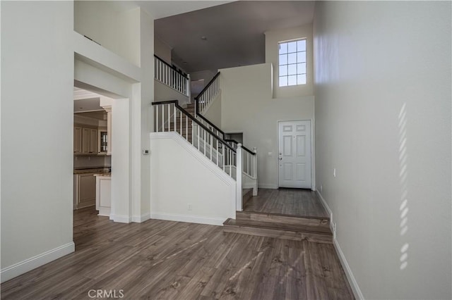 interior space featuring baseboards, a high ceiling, and wood finished floors