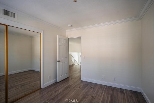 unfurnished bedroom featuring baseboards, dark wood-style flooring, visible vents, and crown molding