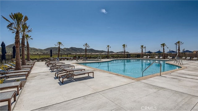 pool featuring a patio area, fence, and a mountain view