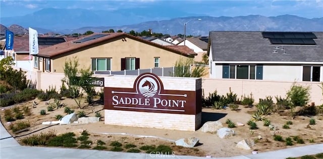 community / neighborhood sign with a mountain view and fence