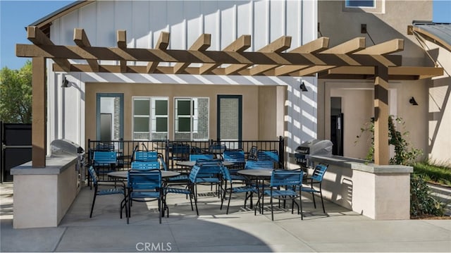 view of patio featuring exterior kitchen, grilling area, a pergola, and outdoor dining space