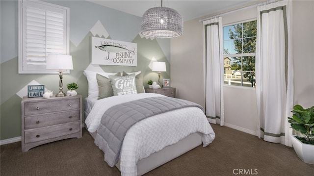 bedroom with dark colored carpet and baseboards