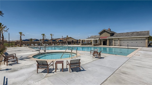 community pool with a hot tub, fence, and a patio