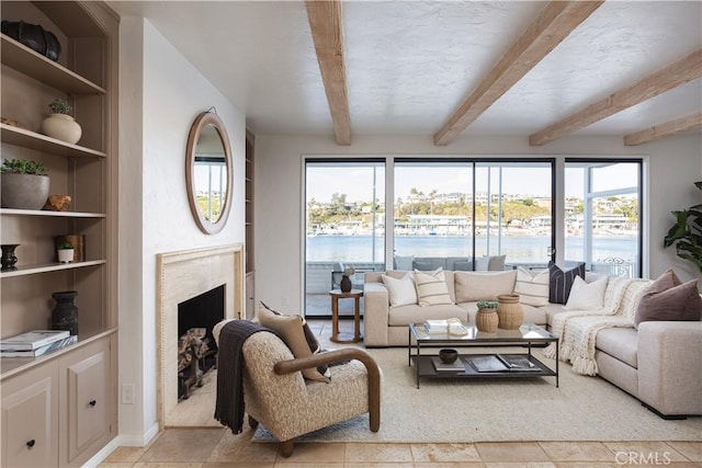living area with a premium fireplace, built in features, beam ceiling, and a water view