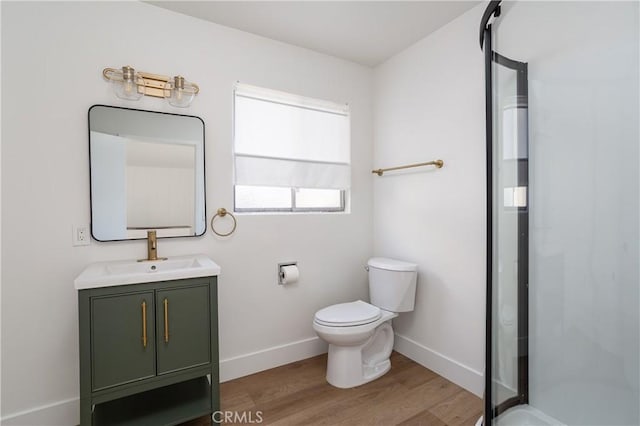 full bath featuring toilet, a shower stall, vanity, wood finished floors, and baseboards