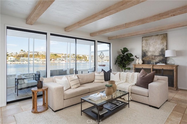 living room with a water view, stone tile floors, and beamed ceiling