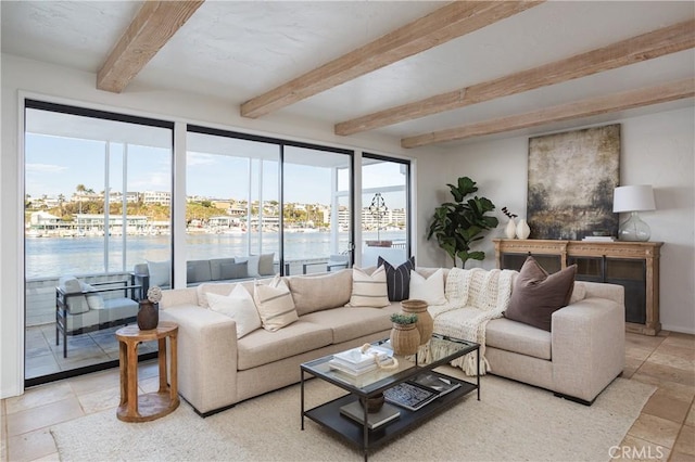 living area featuring beamed ceiling, stone tile floors, and a water view