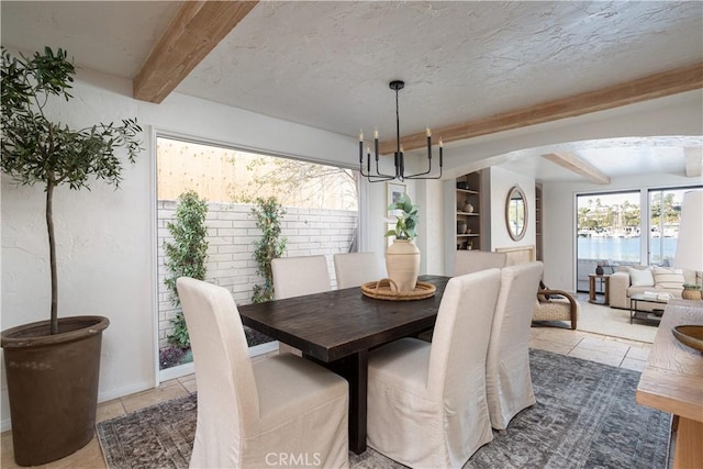 dining space featuring an inviting chandelier, a textured ceiling, arched walkways, and beamed ceiling