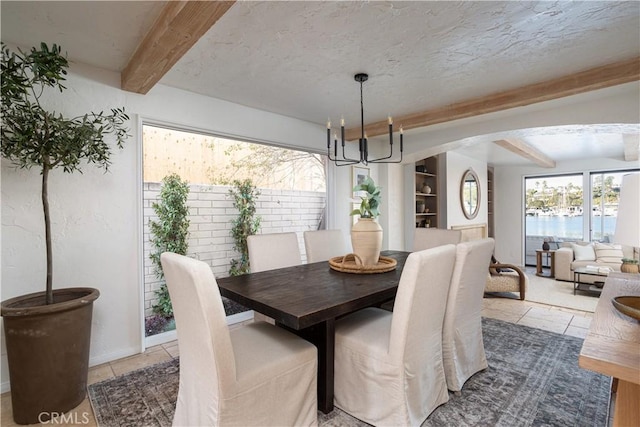 dining area with beamed ceiling, baseboards, arched walkways, and a notable chandelier