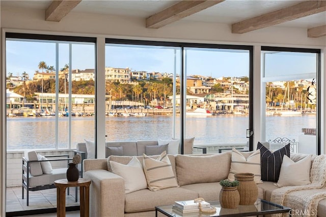 living area with a water view, plenty of natural light, and beamed ceiling