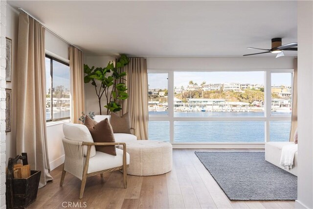 living area featuring a healthy amount of sunlight, wood finished floors, and a water view
