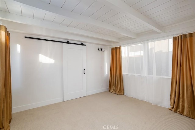 empty room featuring light colored carpet, beamed ceiling, baseboards, and a barn door