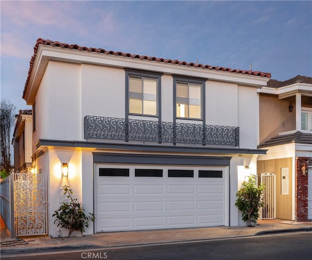 view of front of house featuring stucco siding, a tile roof, concrete driveway, and a garage