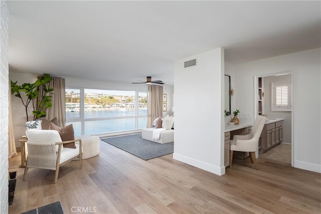 sitting room with light wood finished floors, baseboards, visible vents, and a wealth of natural light