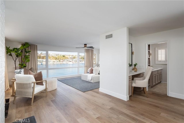 living room featuring light wood-type flooring, visible vents, baseboards, and ceiling fan
