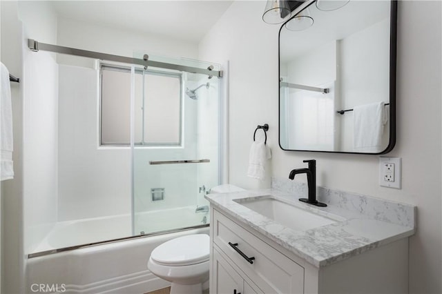 bathroom featuring combined bath / shower with glass door, vanity, and toilet