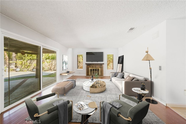 living room featuring a brick fireplace, visible vents, and wood finished floors