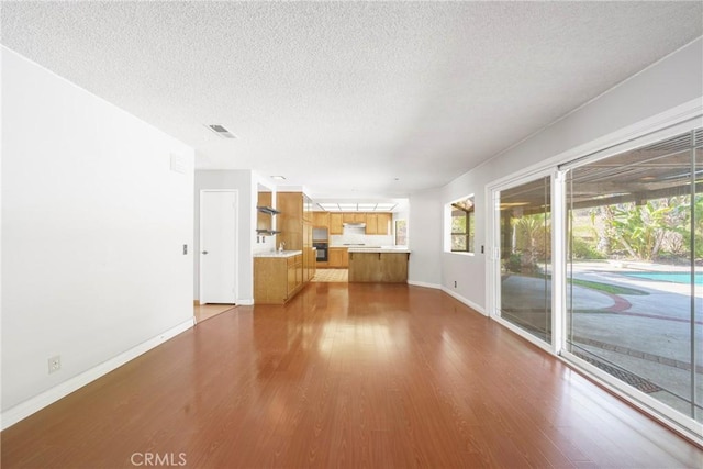 49 Village Loop Rd, Pomona, CA 91766 - unfurnished living room with baseboards, a textured ceiling, and wood finished floors