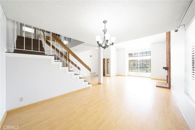 49 Village Loop Rd, Pomona, CA 91766 - unfurnished living room featuring a chandelier, wood finished floors, stairs, and a textured ceiling