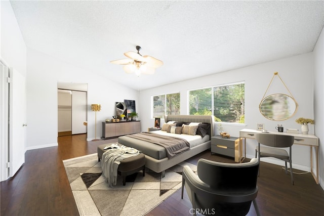 bedroom featuring lofted ceiling, a textured ceiling, wood finished floors, and baseboards