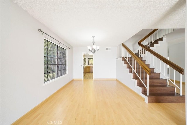 49 Village Loop Rd, Pomona, CA 91766 - foyer entrance with a chandelier, wood finished floors, stairs, a textured ceiling, and baseboards