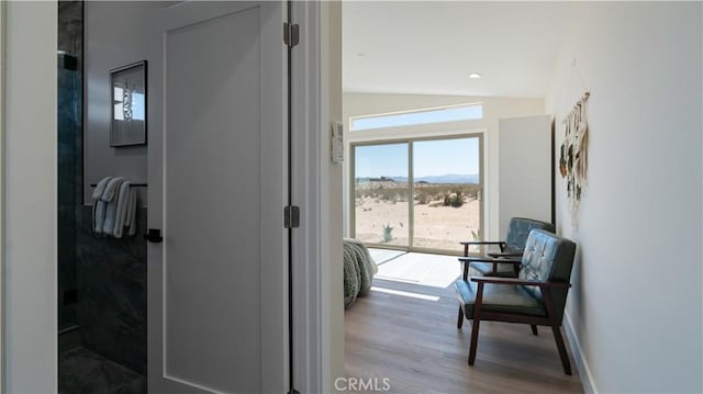 hallway featuring vaulted ceiling, wood finished floors, and baseboards