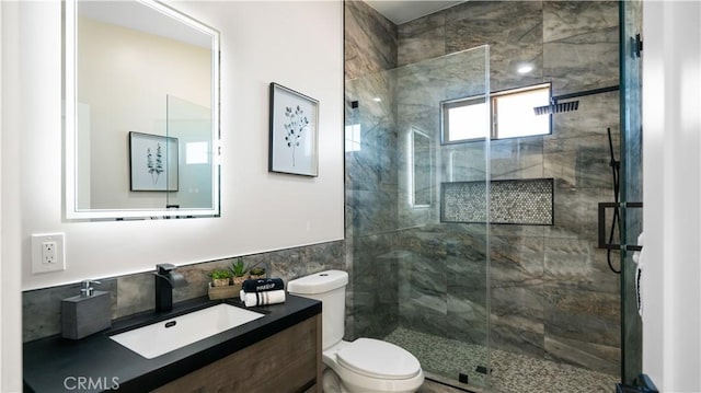 bathroom with vanity, a shower stall, toilet, and tile walls