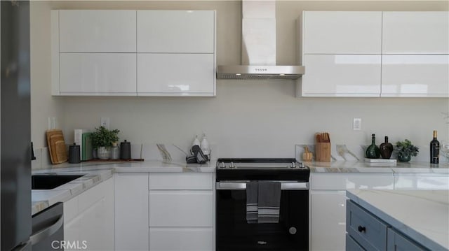 kitchen with stainless steel appliances, white cabinetry, light stone counters, and wall chimney exhaust hood