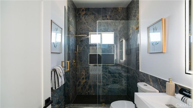 bathroom featuring a stall shower, vanity, toilet, and tile walls