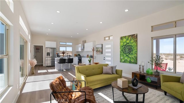 living area featuring recessed lighting, baseboards, plenty of natural light, and light wood finished floors