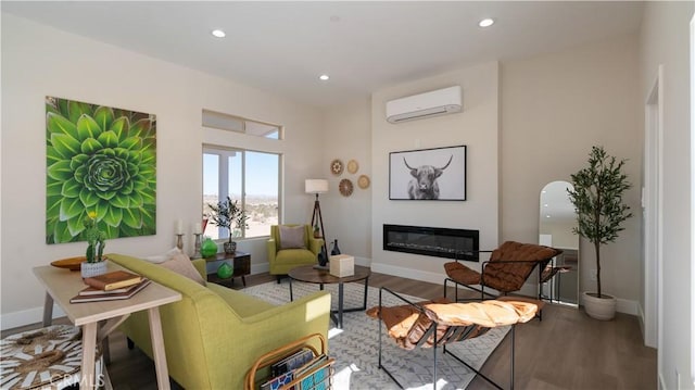 sitting room featuring recessed lighting, a glass covered fireplace, wood finished floors, and a wall mounted AC