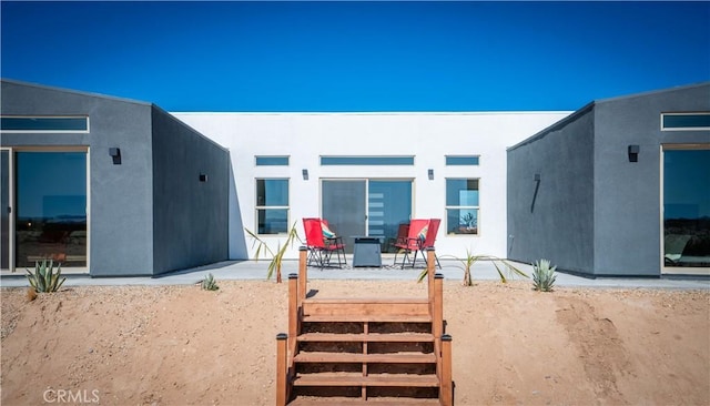 rear view of property with a patio area and stucco siding