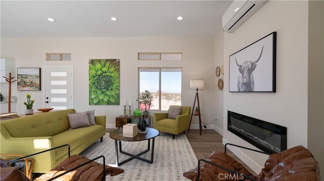 living room featuring a wall mounted air conditioner, a glass covered fireplace, light wood-style flooring, and recessed lighting