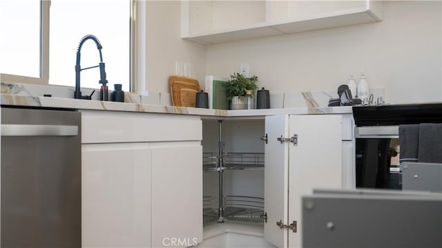 kitchen with light countertops, stainless steel dishwasher, modern cabinets, and white cabinetry