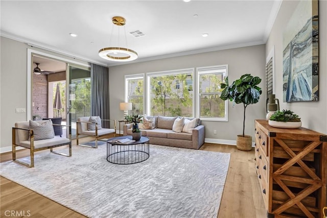 living room with light wood-type flooring, ornamental molding, plenty of natural light, and visible vents