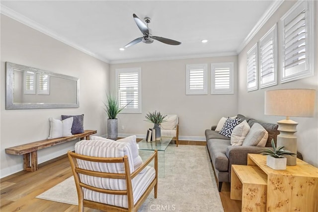 living area with light wood finished floors, baseboards, ornamental molding, and ceiling fan