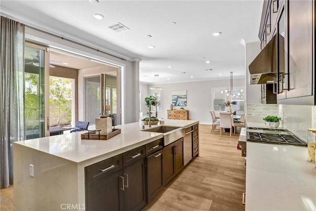 kitchen with recessed lighting, light countertops, a sink, an island with sink, and light wood-type flooring